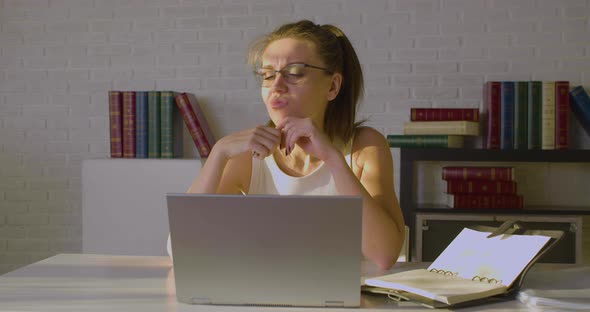 Front View of a Young Woman Works in an Office  She Enters Data Into a Laptop