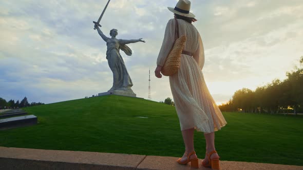 A young girl looking at Mother Motherland on the Mamayev Kurgan at sunset