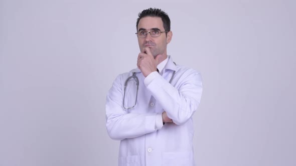 Handsome Man Doctor Thinking While Wearing Eyeglasses Against White Background