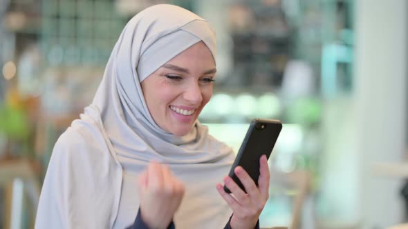 Excited Arab Woman Celebrating Success on Smartphone 