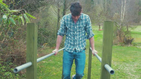 Young man jumps to parallel bars and begins doing dips