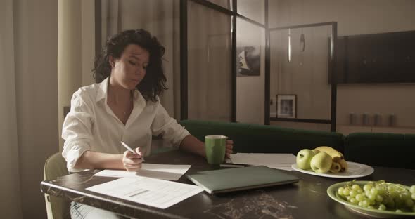 Businesswoman Drinking Coffee and Making Notes