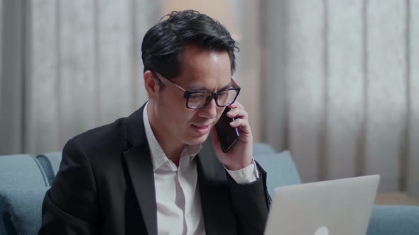 Businessman In Jacket And Shorts Answering The Call And Talking On Phone While Working With A Laptop