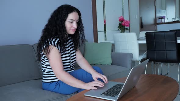 Woman Working on Laptop, Sitting on Sofa at Home, Businesswoman Sits at Home Works Remotely on