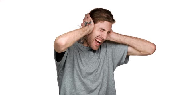 Portrait of Tall Caucasian Guy Covering Ears and Screaming Because of Annoying Noise or Loud Music