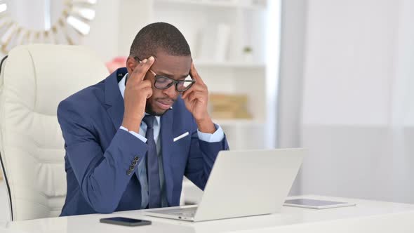 Young African Businessman with Laptop Having Headache in Office