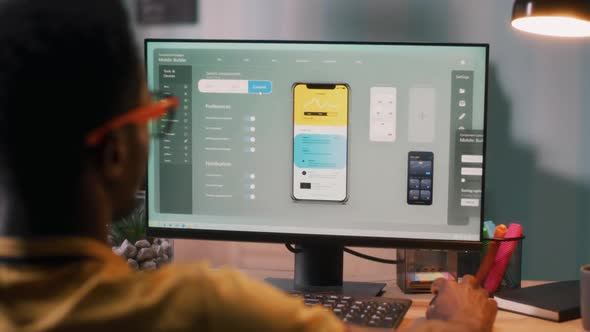 Black Male Creating Cellphone App on Computer