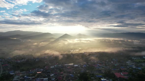 Landscape view of the city of rural village in valley on foggy day while the sun is raising by drone