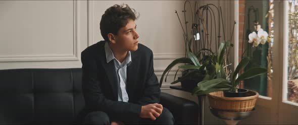 Young man sitting on a sofa staring out the window