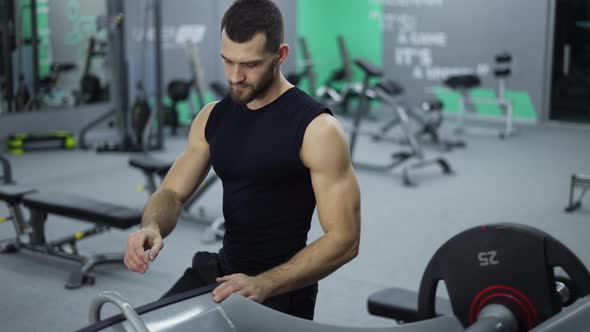 Man Puts Additional Weights on a Barbell