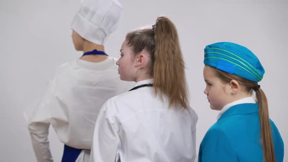 Confident Serious Caucasian Girl Doctor Turning Crossing Hands Posing with Blurred Little Stewardess