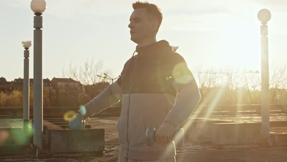 Young and fit man having evening workout outdoor. Urban sunset background.