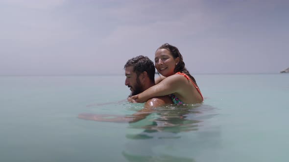 A Cinematic Shot of a Multicultural Couple of Young Lovers Piggybacking in the Sea Water
