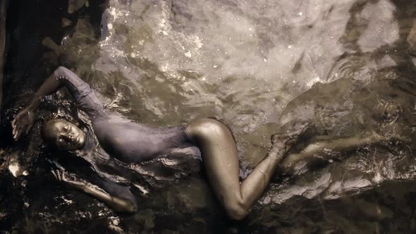 Graceful Woman in Water with Golden Pigment Skin Is Covered By Gold Dye Slow Motion