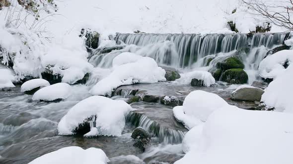 Wonderful frozen foot of a waterfall with a powerful stream of water at winter carpathian mountains