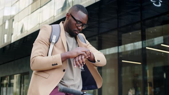 Young Afro-American Businessman on Bike Checking Time on Wristwatch