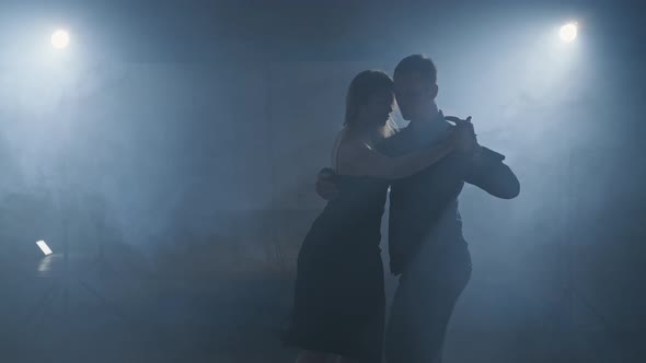 Silhouette of Dancers in Dark Studio with Lights. Woman and Man Dancing Tango