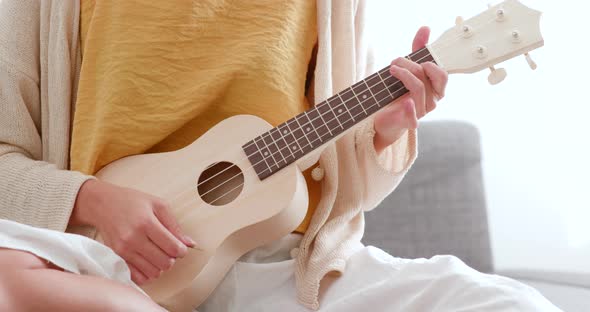 Woman play ukulele at home