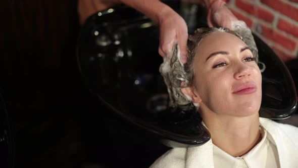 Closeup Smiling Satisfied Young Beautiful Woman in Beauty Salon and Male Hands Shampooing Hair in