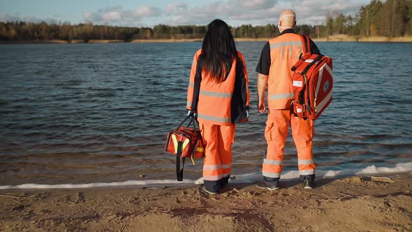 Two Proud Paramedics Posing Near Blue Lake on Sunny Day