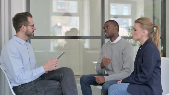 Businessman with Tablet Interviewing African Businessman and Young Woman