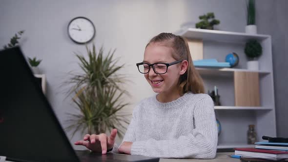 Girl in Gray Knitted Sweater in Eyeglasses Smiling from Amusing Video on Screen of Computer