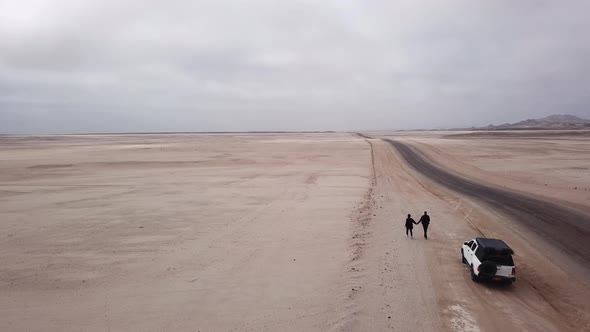 Young Couple Walks on Highway Car at Roadside Parked in Desert