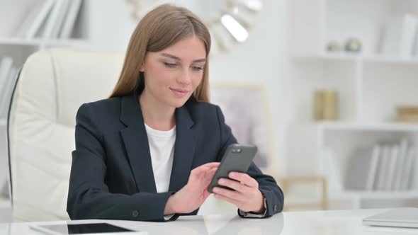 Serious Businesswoman Using Smartphone in Office
