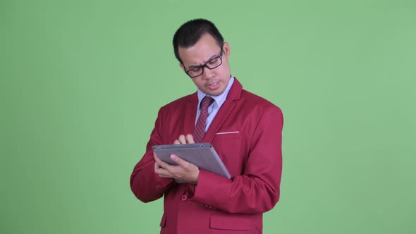 Happy Asian Businessman Talking While Using Digital Tablet