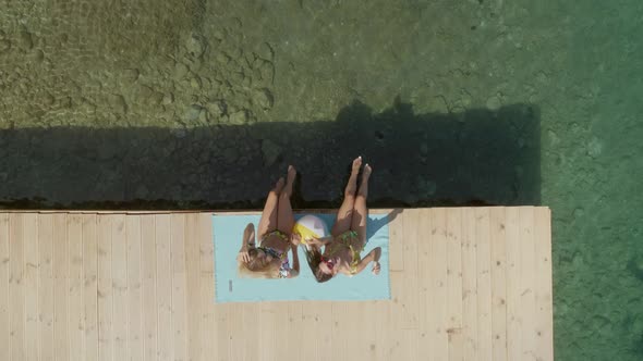 Aerial view of two women sits on wooden deck in Panagopoula, Greece.