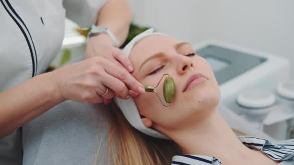 Closeup Shot of Facial Massage with a Jade Roller on Woman's Face at Beauty Salon