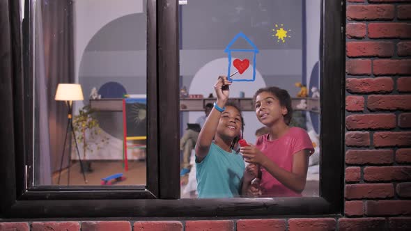 Smiling Dark-skinned Girls Painting on Window