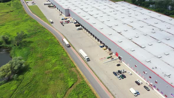 Buildings of logistics center, warehouses near the highway, truck parking process, view from height,