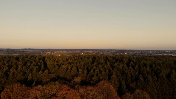 Aerial view over a forest in the Bavarian flat land area, during sunrise hours.
