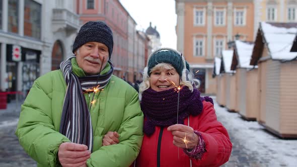 Senior Couple with Burning Sparklers Bengal Lights Celebrating Anniversary Making a Kiss on Street