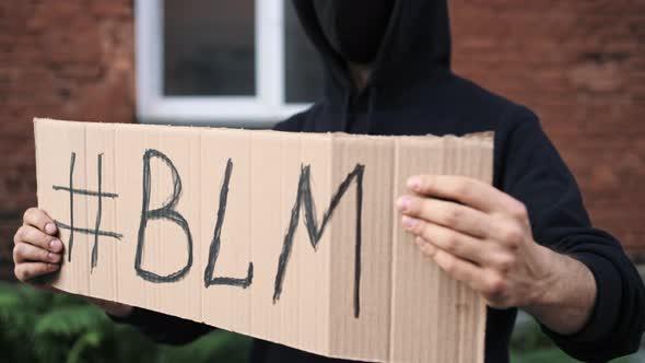 Man in Mask Stands with Cardboard Poster in Hands  BLACK LIVES MATTER