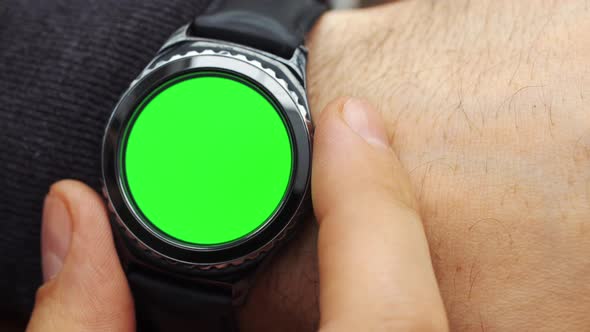 Man Hands Gestures on a Round Screen Modern Smartwatch with a Green Screen Chroma Key Content, Close