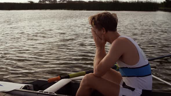 Male rower crying on the boat on the lake