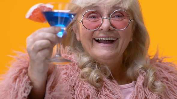 Chic Aged Lady Showing Blue Cocktail Glass in Hand, Stylish Grandmother Relax