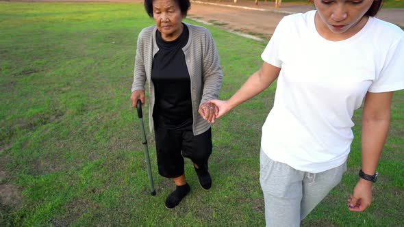 slow-motion of woman hold hands of elderly woman and walking in the park