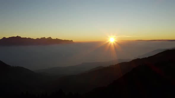 Slow aerial shot of the Sun setting over sea of fog. covering Lake Léman, Switzerland