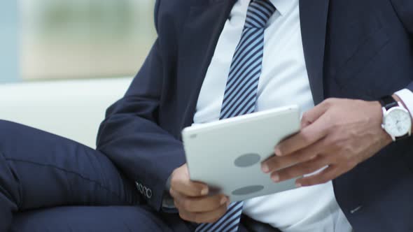 Businessman Sitting on Couch and Texting on Tablet