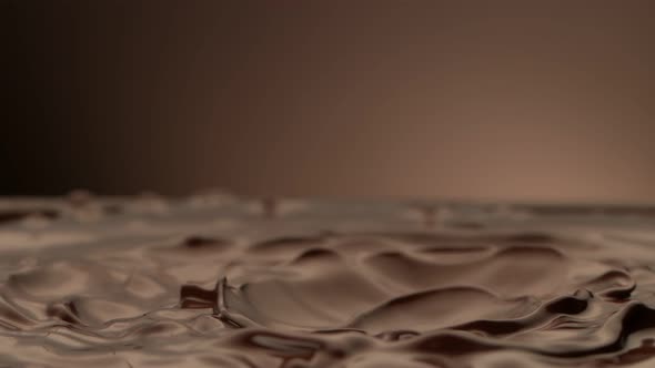 Super Slow Motion Shot of Waving Melted Chocolate on Brown Gradient Background at 1000 Fps