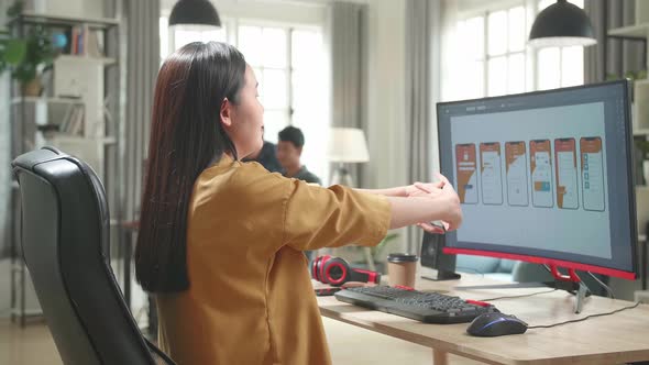 Asian Female Mobile Application Developer Stretching While Works With Graphics On Computer In Office