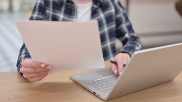 Female Hands Holding Paper and Typing on Laptop Close Up