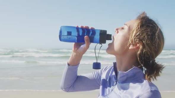 Athletic woman drinking water on the beach