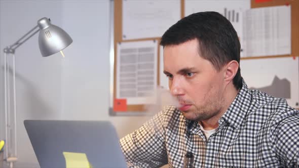 Slow Motion Shot of Man Smoking an Electronic Cigarette in His Office