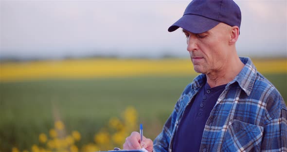 Agriculture Farmer Writing on Clipboard While Examining Agricultural Field