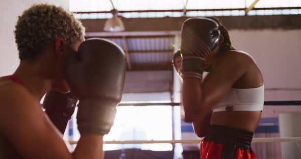 Two mixed race women training in boxing ring