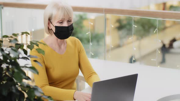 Proud Confident Mature Businesswoman in Protective Mask Working in Office Typing on Laptop Using